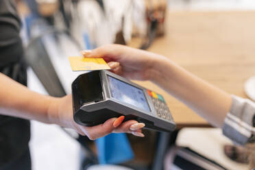 Frau zahlt mit Kreditkarte an Kellnerin im Food Court - JRVF01259