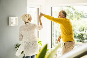 Mature man holding hand of woman while dancing at home - UUF24107