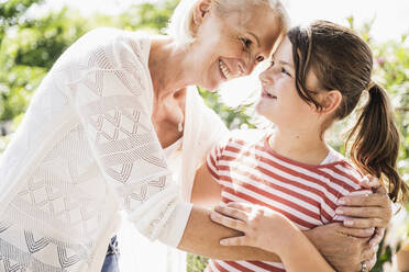 Lächelnde Enkelin schaut Großmutter an einem sonnigen Tag an - UUF24110