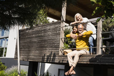 Smiling woman standing behind man and girl at balcony - UUF24122