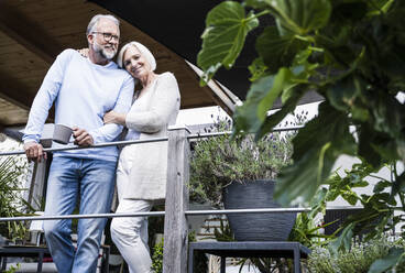 Smiling woman leaning on man while standing by railing - UUF24129