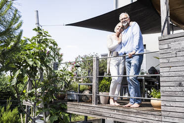 Lächelndes Paar steht bei Pflanzen auf dem Balkon - UUF24133