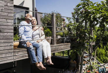 Gelassenes Paar sitzt zusammen auf dem Balkon an einem sonnigen Tag - UUF24138