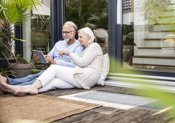 Man using digital tablet while sitting at balcony - UUF24140