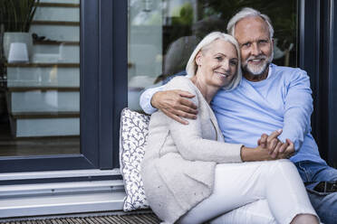 Man holding hand of woman while sitting at balcony - UUF24147