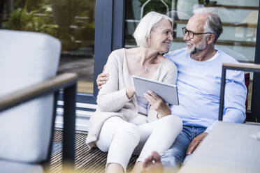 Woman holding digital tablet while sitting at balcony - UUF24148