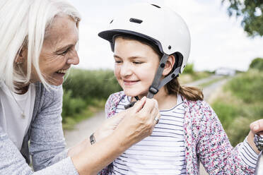 Woman helping girl with cycling helmet - UUF24173