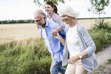 Glückliche Familie spielt beim gemeinsamen Laufen auf der Wiese - UUF24179