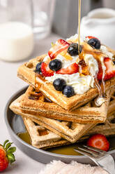 Ahornsirup auf einem Stapel frischer Waffeln mit Blaubeeren, Erdbeeren und Eiscreme - FLMF00611