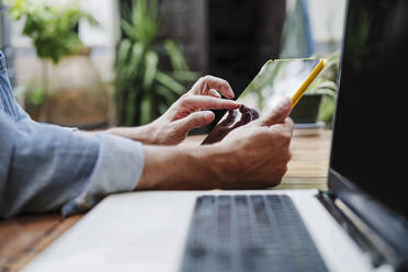 Männlicher Freiberufler, der im Hinterhof ein digitales Tablet benutzt - EBBF04338