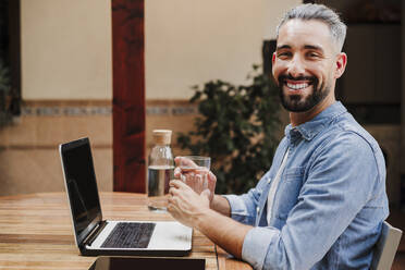 Mid adult businessman having water at desk - EBBF04341