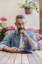 Male freelance worker using digital tablet at desk - EBBF04354