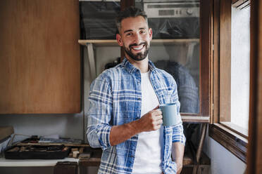 Male professional holding coffee mug at workshop - EBBF04384