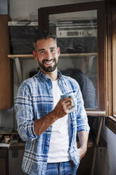 Handsome businessman having coffee at workshop - EBBF04385