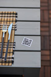 Hoher Winkel des QR-Codes der Speisekarte eines asiatischen Restaurants auf dem Tisch mit Serviette und Messer und Gabel - ADSF28327