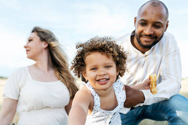 Glückliche multiethnische Familie mit süßer kleiner Tochter genießt Sommerpicknick in der Natur - ADSF28356