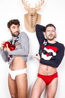 Couple of adult gay lovers in underwear and Xmas sweaters with decorative  red balls standing against