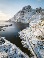 Luftaufnahme einer Panoramastraße entlang der Küstenlinie im Winter in der Nähe der Stadt Ramberg, Lofoten, Norwegen. - AAEF11528