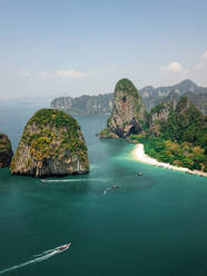 Luftaufnahme von winzigen Schnellbooten, die die riesigen Kalksteinfelsen und Inseln im türkisblauen Meer erkunden, ein tropisches Paradies, Phra Nang, Krabi, Phuket, Thailand. - AAEF11628