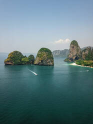 Luftaufnahme von winzigen Schnellbooten, die die riesigen Kalksteinfelsen und Inseln im türkisblauen Meer erkunden, ein tropisches Paradies, Phra Nang, Krabi, Phuket, Thailand. - AAEF11630