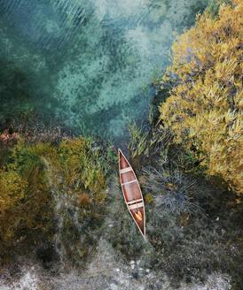 Aerial view of classic Canadian canoe paddling on small pond lake with reeds and bushes in Tekapo, South Island, New Zealand - AAEF11632