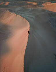 Luftaufnahme von Person zu Fuß auf Sand mit rosa Sonnenuntergang Sonnenaufgang auf Lancelin Sand Dunes, Western Australia - AAEF11647