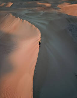 Aerial view of person walking on sand with pink sunset sunrise on Lancelin Sand Dunes, Western Australia - AAEF11647