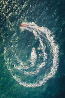 Luftaufnahme von Schnellboot und Wasserskifahrer bei Sonnenuntergang, Langzeitbelichtung, Hamble Le Rice, Southampton Water, Vereinigtes Königreich - AAEF11797
