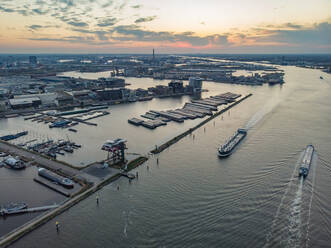 Luftaufnahme des Stadthafens mit angedockten Booten bei Sonnenuntergang entlang des Buiten IJ-Kanals in Amsterdam, Nordholland, Niederlande. - AAEF11908