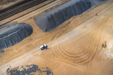 Aerial view of a white vehicle parked along the railway in Namibian desert Moon near Swakomund, Namibia. - AAEF12020