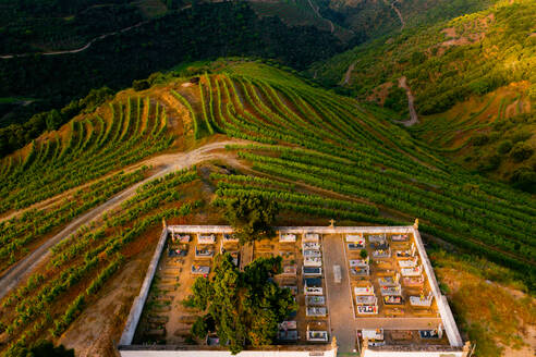 Luftaufnahme eines Friedhofs oberhalb der Weinbergterrassen, die für die Herstellung von Portwein genutzt werden, in Desejosa, Tabua√ßo, Douro-Tal, Portugal - AAEF12050