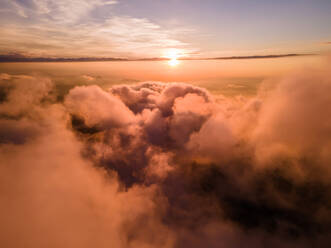 Luftaufnahme der vom Sonnenuntergang warm beleuchteten Wolken in Schwyz, Schweiz - AAEF12085