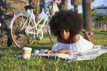 Afro-Frau mit geschlossenen Augen, die sich auf einer Picknick-Decke entspannt - VEGF04774