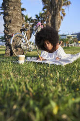 Afro-Frau entspannt sich auf einer Decke in einem öffentlichen Park - VEGF04776