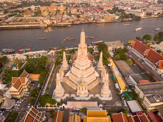 Luftaufnahme der Wat Arun Pagode entlang des Chao Phraya Flusses bei Sonnenuntergang mit einem städtischen Wohnviertel im Hintergrund, Khet Phra Nakhon Bezirk, Bangkok, Thailand. - AAEF12140