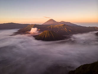 Luftaufnahme des von Wolken umgebenen Mount Bromo bei Sonnenuntergang, eines aktiven Vulkans in der Nähe der Stadt Probolinggo, Ost-Java, Indonesien. - AAEF12171