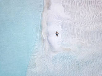 Aerial view of lone man sunbathing on sandy coastal beach of Thulusdhoo island - KNTF06288