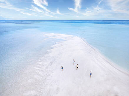 Aerial view of four people walking along sandy coast of Thulusdhoo island - KNTF06291