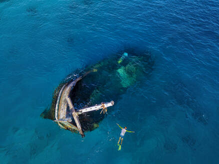 Luftaufnahme eines einsamen Mannes beim Schnorcheln um ein versunkenes Schiffswrack - KNTF06298