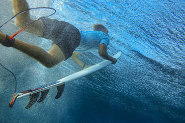 Unterwasseransicht eines jungen Mannes beim Surfen im blauen Wasser des Süd Male Atolls - KNTF06300