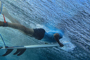 Unterwasseransicht eines jungen Mannes beim Surfen im blauen Wasser des Süd Male Atolls - KNTF06301