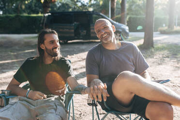 Smiling gay couple holding hands while talking on sunny day - EGHF00134