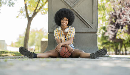 Afro-Frau mit Basketball auf dem Gehweg sitzend - JCCMF03284