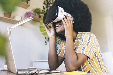 Happy young woman using virtual reality simulator at home - JCCMF03315