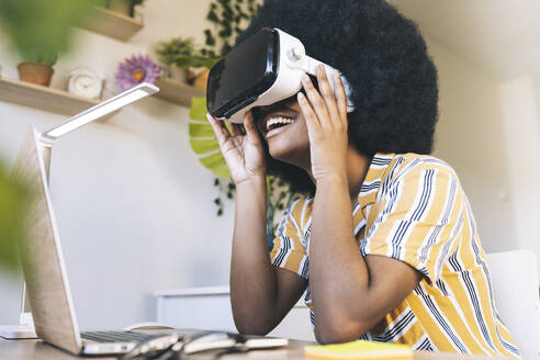 Glückliche junge Frau, die einen Virtual-Reality-Simulator zu Hause benutzt - JCCMF03315