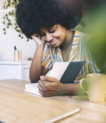 Afro-Frau liest Buch am Schreibtisch - JCCMF03316