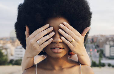 Woman covering eyes of Afro girlfriend with hands at sunset - JCCMF03336