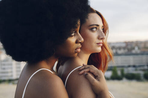 Lesbian couple looking away during sunset - JCCMF03351