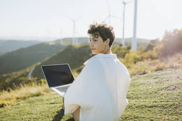 Woman with laptop sitting on mountain - GMCF00170