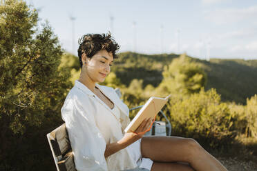 Woman reading book while sitting on bench - GMCF00183